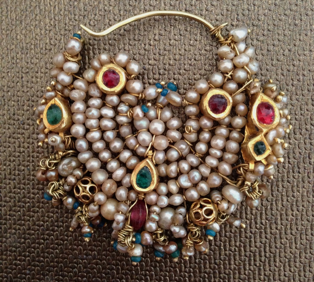 Ett utsmyckat antikt halsband med flera strängar av pärlor, guld och färgstarka ädelstenar som visar på traditionellt hantverk.